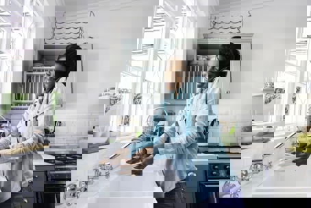 a woman using her phone while doing the dishes